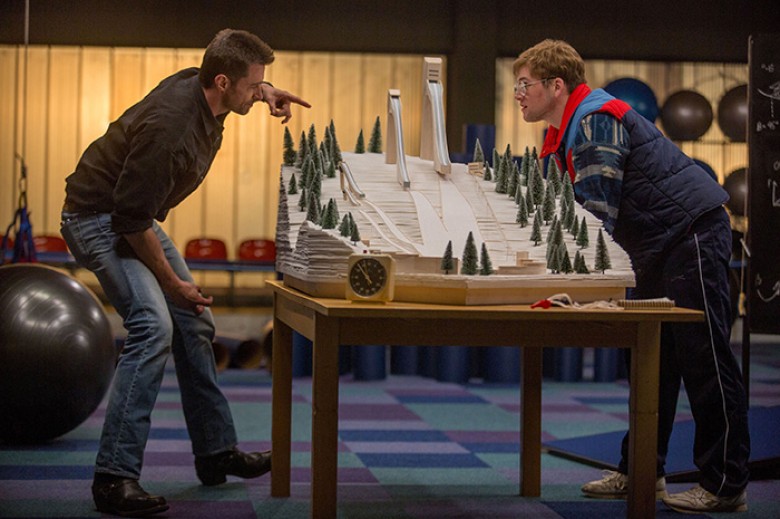 Bronson (Hugh Jackman) puts things in perspective for aspiring ski jumper Eddie (Taron Egerton). Larry Horricks – TM and © 2015 Twentieth Century Fox Film Corporation. All Rights Reserved. Not for sale or duplication.