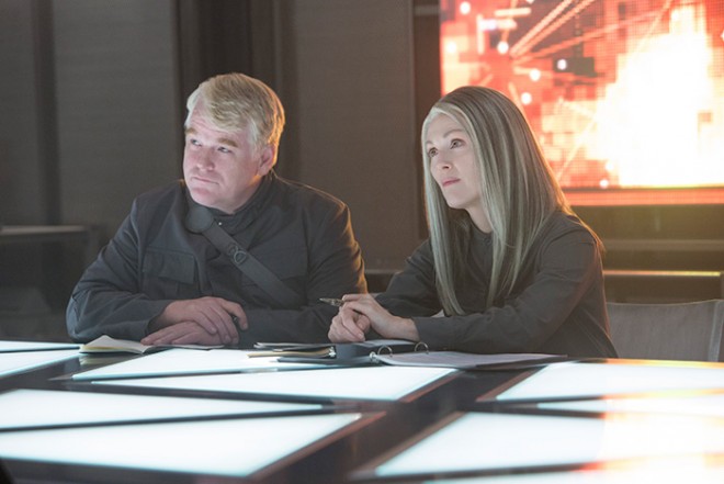 Plutarch Heavensbee (Philip Seymour Hoffman) and President Coin (Julianne Moore) in THE HUNGER GAMES: MOCKINGJAY – PART 1. Photo Credit: Murray Close