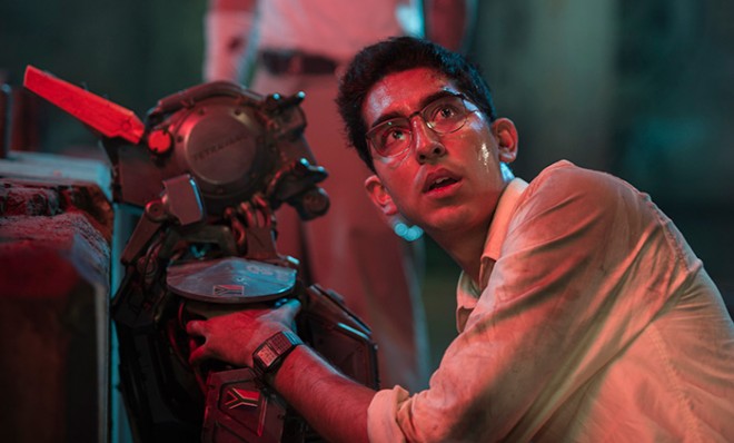 Deon (Dev Patel) boots up Chappie (Sharlto Copley) in Columbia Pictures’ action-adventure CHAPPIE. © 2015 CTMG, Inc. All rights reserved. Artist: Stephanie Blomkamp